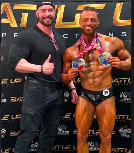 Bernardo Costa standing with a male competitor holding medals